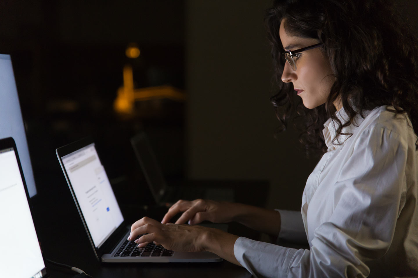 serious-businesswoman-using-laptop-dark-office